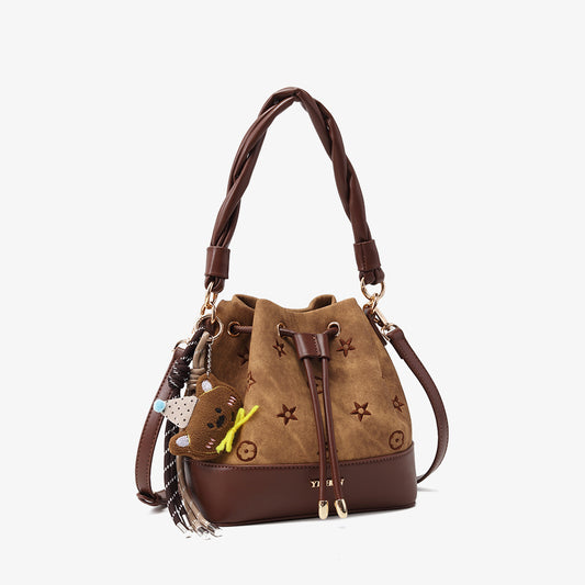 Lucky Charm Couture Crossbody Bag featuring a brown suede exterior with star embellishments and a braided handle.